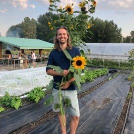 UW Farm staff holding a sunflower in a field