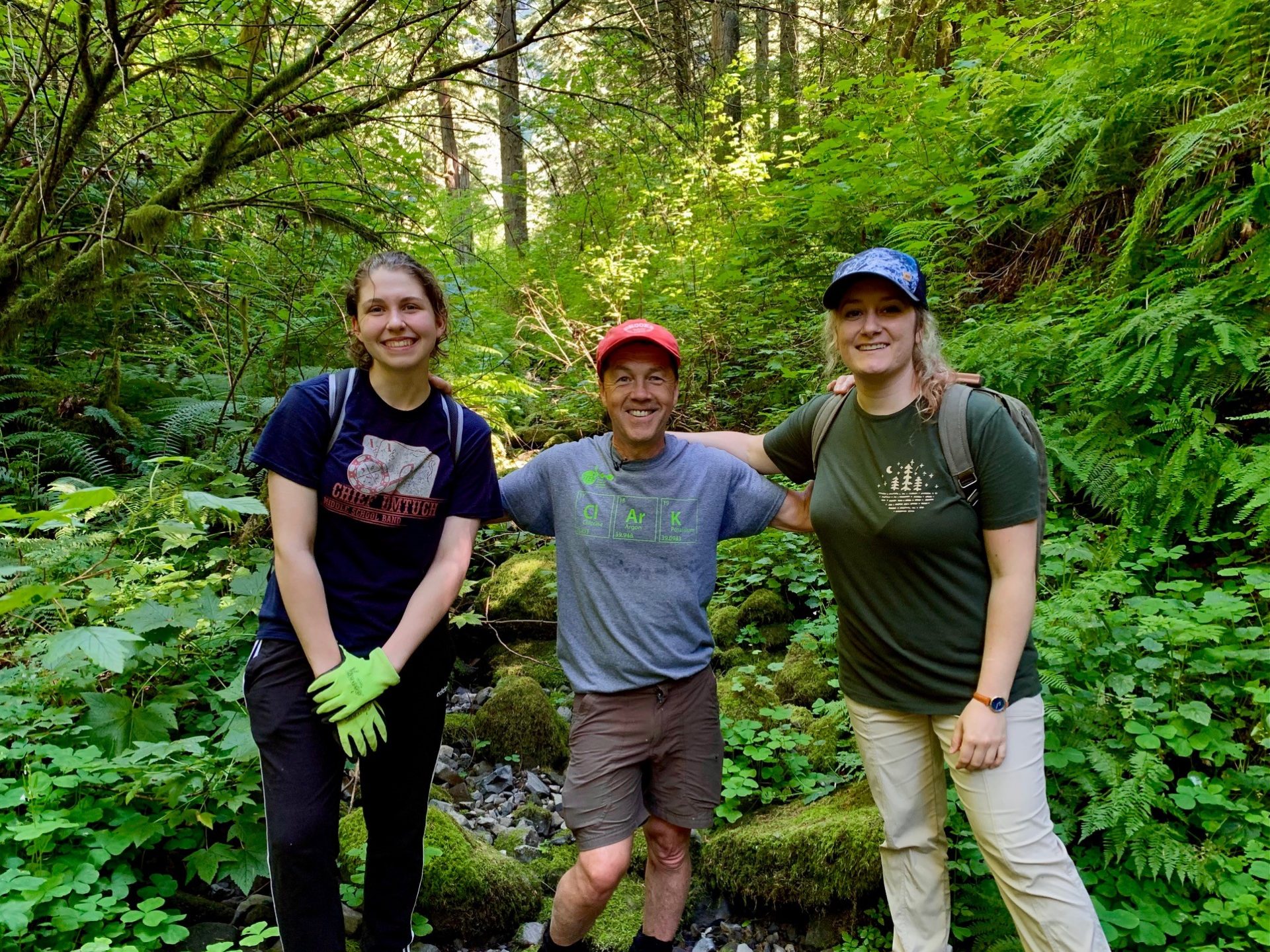 Three hikers posing for a picture in the forest.