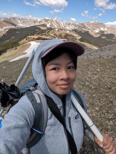 A person smiling with mountains behind them. 