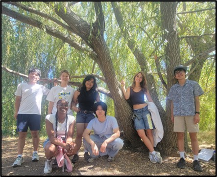 Image of high school interns posing around a tree. 