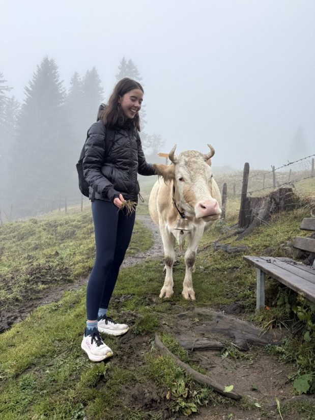 Student Remi, with a cow on a farm